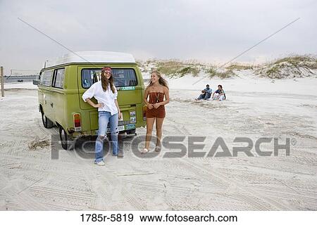Portrait of young women in hippie fashion standing by van at beach View Large Photo Image Stock Photo - Portrait of young women in hippie fashion standing by van at beach. Fotosearch
