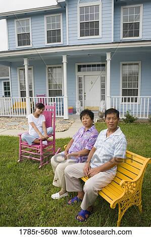 Stock Photo - Pregnant woman and her parents seated in front lawn of house. Fotosearch