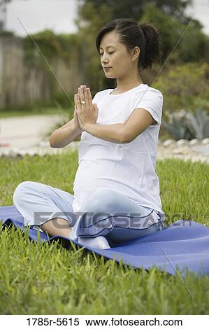 Stock Photography - Pregnant woman in yoga position on lawn. Fotosearch
