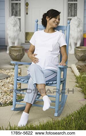 Pregnant woman sitting on a rocking chair in front of house View Large Photo Image Stock Image - Pregnant woman sitting on a rocking chair in front of house. Fotosearch