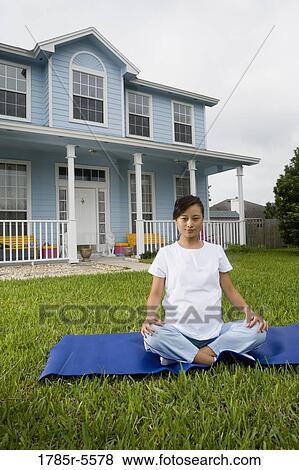 Stock Photo - Pregnant woman sitting on exercise mat in front of house. Fotosearch