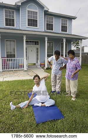 Stock Image - Pregnant woman stretching while her parents stand by and watch. Fotosearch