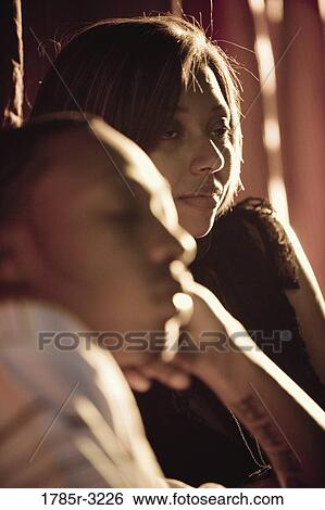 Stock Photograph - Profile of young couple in dimly lit room. Fotosearch