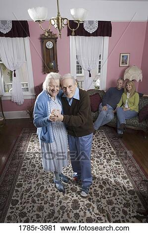 Stock Image - Senior couple dancing in living room. Fotosearch