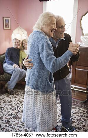 Senior couple dancing in living room while their adult children watch View Large Photo Image Stock Photo - Senior couple dancing in living room while their adult children watch. Fotosearch