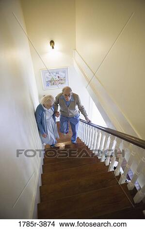 Senior couple helping one another carefully climb up stairs View Large Photo Image Picture - Senior couple helping one another carefully climb up stairs. Fotosearch