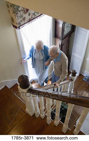Senior couple helping one another carefully climb up stairs View Large Photo Image Stock Image - Senior couple helping one another carefully climb up stairs. Fotosearch
