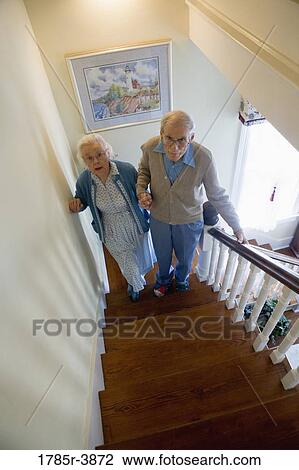 Senior couple helping one another carefully climb up stairs View Large Photo Image Stock Image - Senior couple helping one another carefully climb up stairs. Fotosearch
