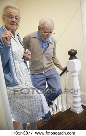 Senior couple helping one another carefully climb up stairs View Large Photo Image Stock Photo - Senior couple helping one another carefully climb up stairs. Fotosearch