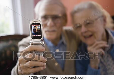 Stock Image - Senior couple photographing themselves with cell phone camera. Fotosearch