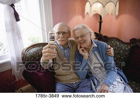 Stock Photo - Senior couple photographing themselves with cell phone camera. Fotosearch