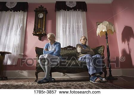 Senior couple sitting on opposite ends of couch View Large Photo Image Stock Photo - Senior couple sitting on opposite ends of couch. Fotosearch