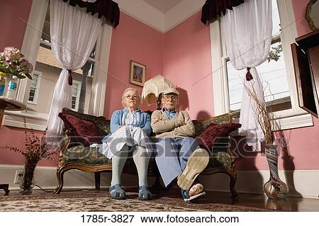 Stock Photo - Senior couple sitting on sofa in living room. Fotosearch