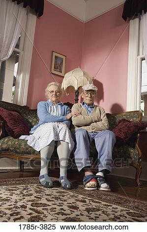 Stock Photography - Senior couple sitting on sofa in living room. Fotosearch