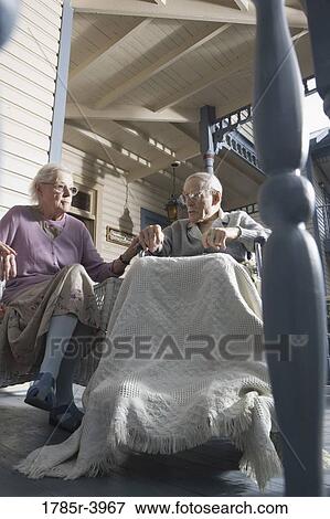 Stock Photo - Senior couple sitting together on front porch. Fotosearch