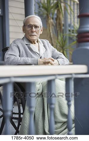 Stock Image - Senior man dozing wheelchair on porch. Fotosearch