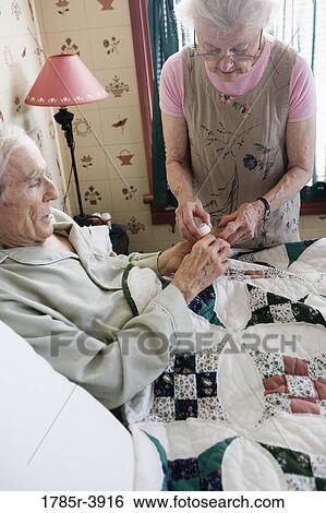 Senior woman dispensing medication to bedridden senior man View Large Photo Image Stock Photograph - Senior woman dispensing medication to bedridden senior man. Fotosearch