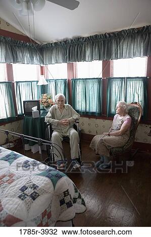 Senior woman sitting next to feeble senior man in wheelchair in bedroom View Large Photo Image Stock Image - Senior woman sitting next to feeble senior man in wheelchair in bedroom. Fotosearch