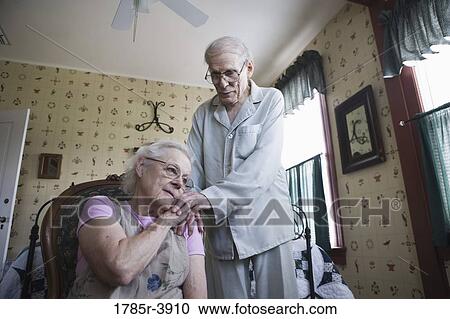 Senior woman sitting with senior man's hand resting on her shoulder View Large Photo Image Stock Image - Senior woman sitting with senior man's hand resting on her shoulder. Fotosearch