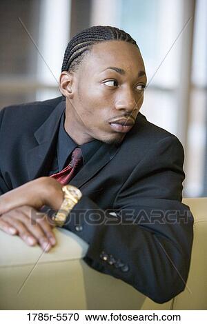 Stock Image - Side view of a business man sitting on sofa. Fotosearch