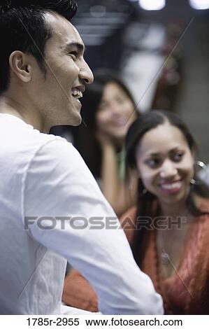 Side view of a young man with friends View Large Photo Image Stock Photography - Side view of a young man with friends. Fotosearch