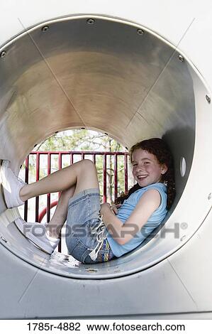 Smiling girl sitting in a tunnel at a playground View Large Photo Image Stock Image - Smiling girl sitting in a tunnel at a playground. Fotosearch