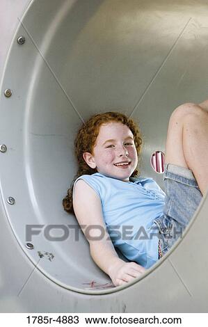 Smiling girl sitting in a tunnel at a playground View Large Photo Image Stock Image - Smiling girl sitting in a tunnel at a playground. Fotosearch