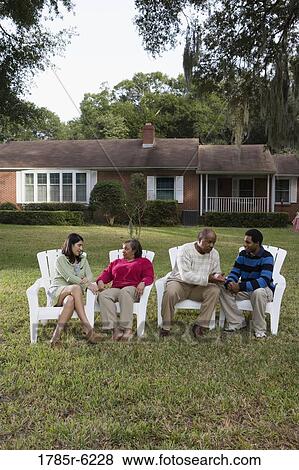 Stock Photo - Son and his girlfriend relaxing with his parents backyard. Fotosearch