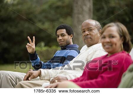 Son giving peace sign with parents in foreground View Large Photo Image Stock Photography - Son giving peace sign with parents in foreground. Fotosearch