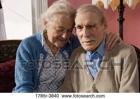 Stoic senior couple sitting on sofa in living room View Large Photo Image Stock Image - Stoic senior couple sitting on sofa in living room. Fotosearch