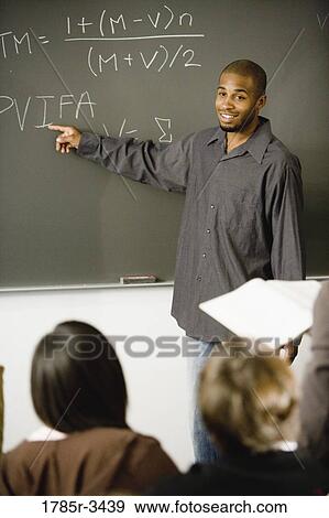 Stock Photo - Student pointing at chalkboard in front of his classmates. Fotosearch