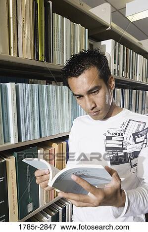 Student standing in the library amidst book stacks View Large Photo Image Stock Photo - Student standing in the library amidst book stacks. Fotosearch