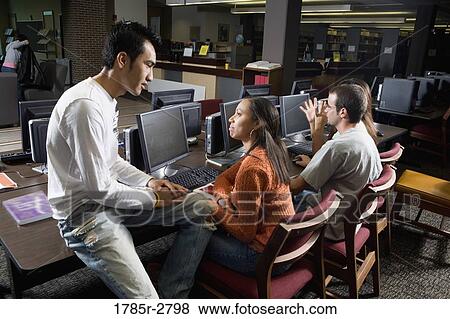 Students conversing while using computers in the library View Large Photo Image Stock Photo - Students conversing while using computers in the library. Fotosearch