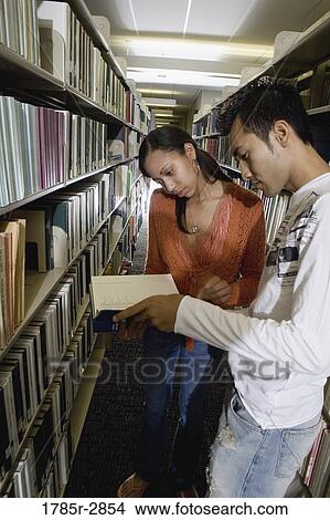 Students in the library looking through book stacks View Large Photo Image Picture - Students in the library looking through book stacks. Fotosearch
