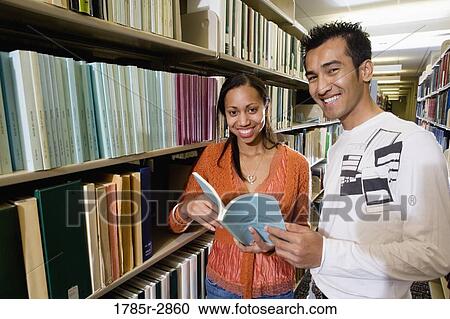 Stock Image - Students in the library looking through book stacks. Fotosearch