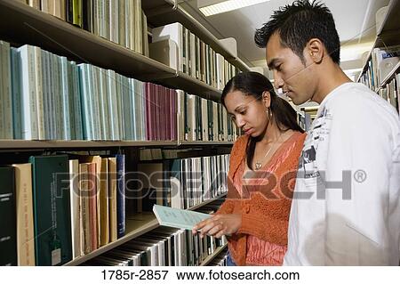 Students in the library looking through book stacks View Large Photo Image Stock Photo - Students in the library looking through book stacks. Fotosearch