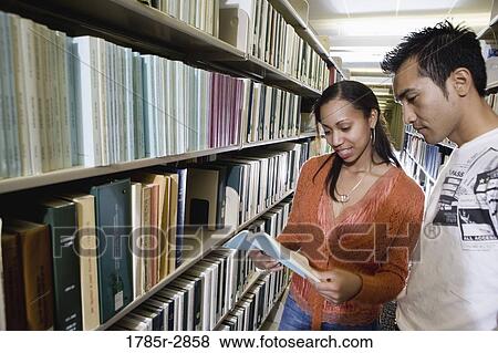 Stock Photo - Students in the library looking through book stacks. Fotosearch