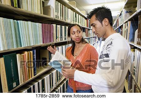 Students in the library looking through book stacks View Large Photo Image Stock Photo - Students in the library looking through book stacks. Fotosearch