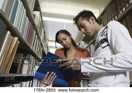 Stock Photography - Students in the library looking through book stacks. Fotosearch