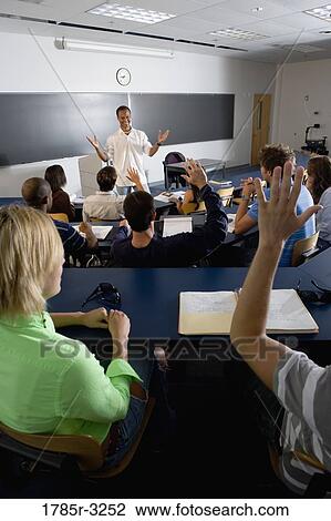 Stock Image - Students raising hands in the classroom. Fotosearch