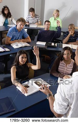 Stock Image - Students raising hands in the classroom. Fotosearch