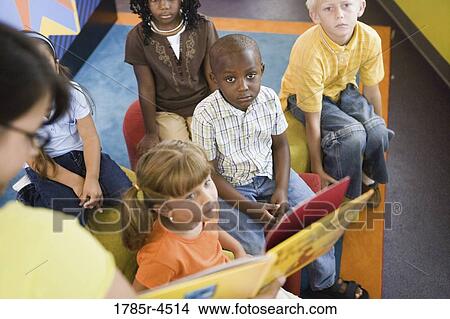 Picture - Students sitting in classroom, watching and listening attentively to their teacher. Fotosearch