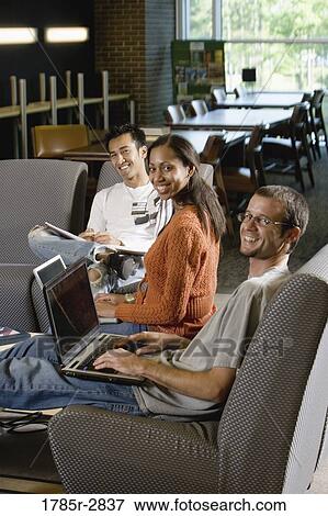 Students with laptop computers in library sitting on sofas studying View Large Photo Image Stock Photo - Students with laptop computers in library sitting on sofas studying. Fotosearch
