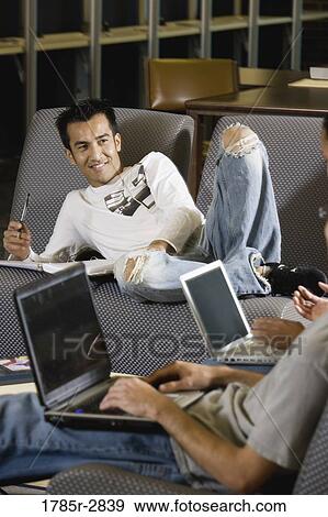 Students with laptop computers in library sitting on sofas studying View Large Photo Image Stock Photo - Students with laptop computers in library sitting on sofas studying. Fotosearch