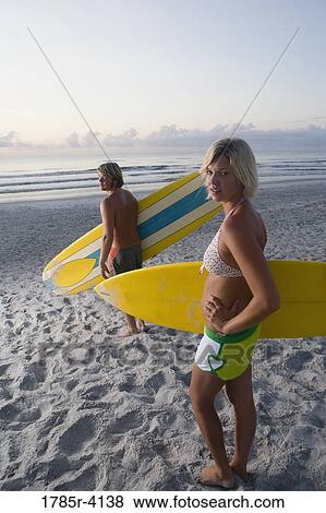 Surfer dude and girl posing on beach at sunrise with surfboards View Large Photo Image Stock Photo - Surfer dude and girl posing on beach at sunrise with surfboards. Fotosearch