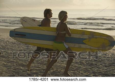 Surfer dude and girl running on beach with surfboards View Large Photo Image Stock Image - Surfer dude and girl running on beach with surfboards. Fotosearch