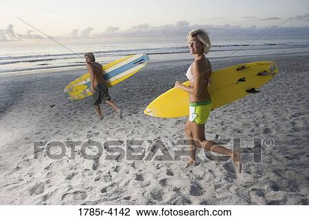 Surfer dude and girl running towards surf with surfboards View Large Photo Image Stock Image - Surfer dude and girl running towards surf with surfboards. Fotosearch