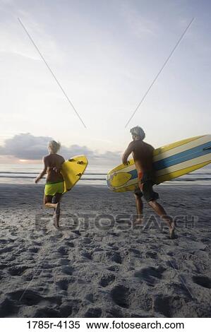 Surfer dude and girl running towards surf with surfboards View Large Photo Image Stock Photography - Surfer dude and girl running towards surf with surfboards. Fotosearch