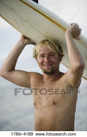 Surfer dude holding a surfboard over his head View Large Photo Image Stock Photo - Surfer dude holding a surfboard over his head. Fotosearch