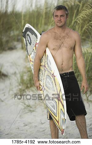 Surfer dude standing on beach with a surfboard View Large Photo Image Stock Image - Surfer dude standing on beach with a surfboard. Fotosearch